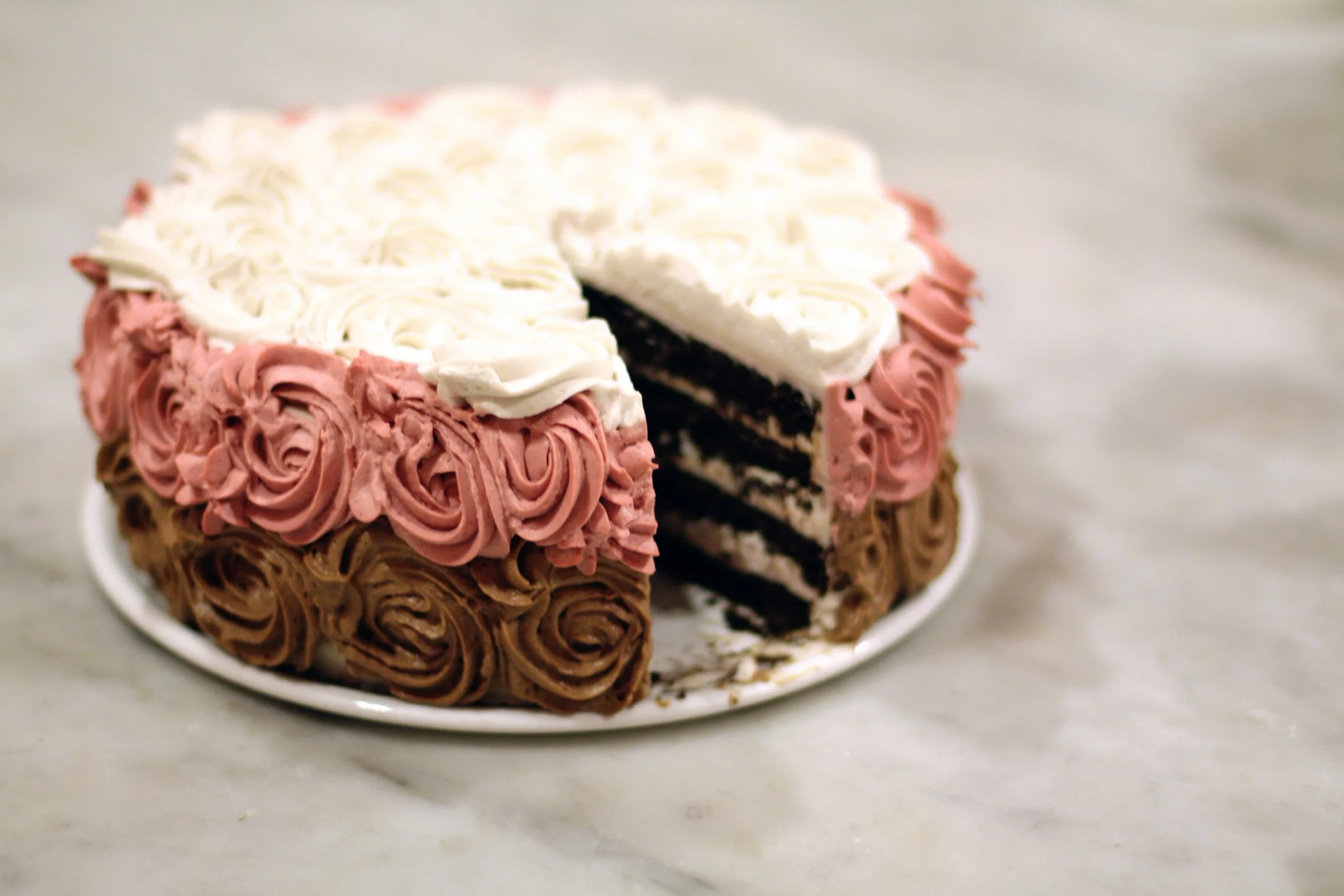 chocolate cake layered with rose frosting, iced with chocolate, rose, and vanilla frosting (raw, gluten-free)