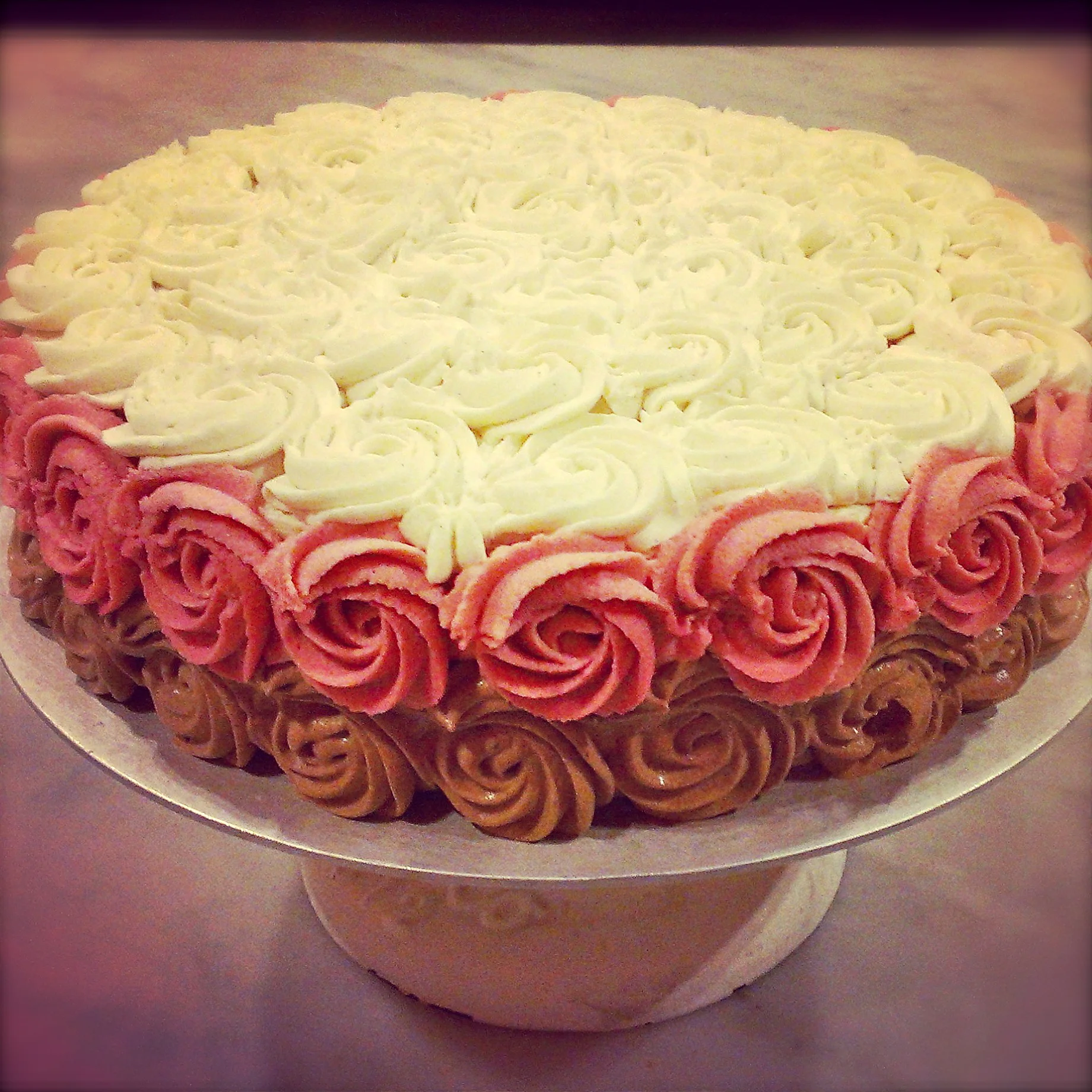 chocolate cake layered with rose frosting, iced with chocolate, rose, and vanilla frosting (raw, gluten-free)