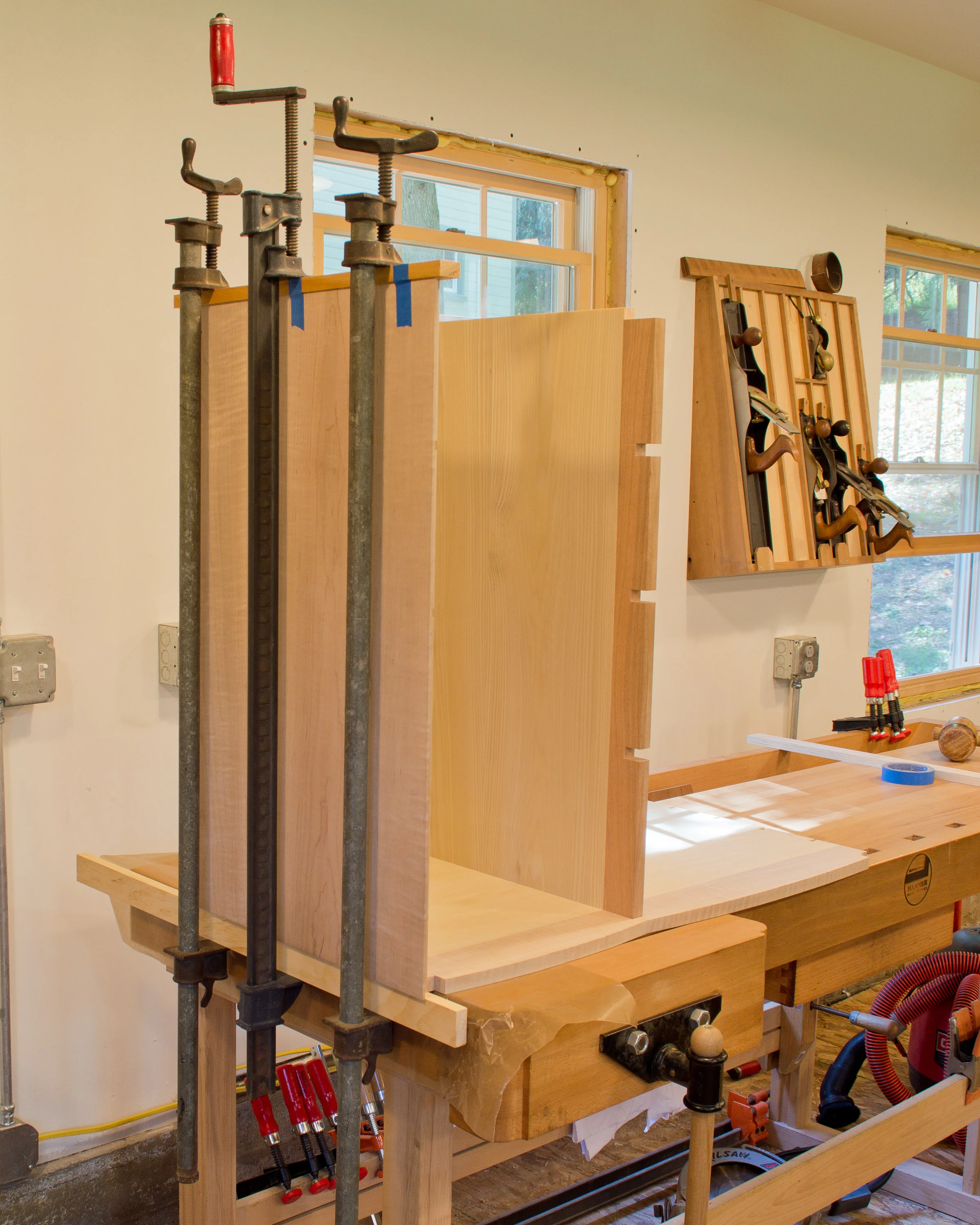 Clamping the half-blind dovetails that join the side to the bottom. The vertical divider has already been assembled to the bottom with a tapered sliding dovetail.