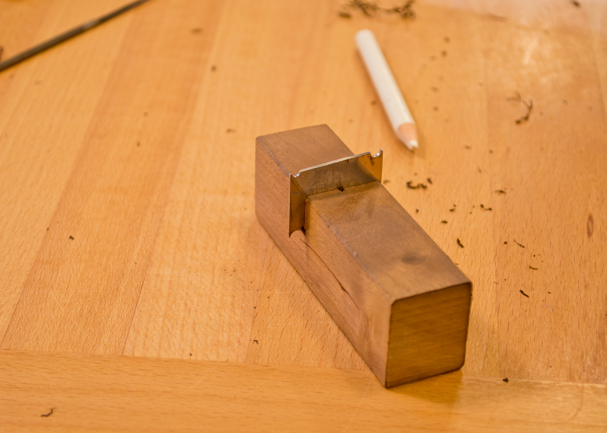 The mighty little scratch stock. A piece of steel and a piece of cherry. Cut a shape into the steel. Insert it into the cherry, and we're ready to scratch beads. 