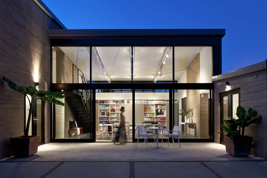 Designed as a series of graduating volumes in response to the neighborhood, this infill project is located in old Mountain View, California. The two-story portion of the house is located to the back of the property to minimize overall appearance when viewed from the quiet residential street. Suspended between two rammed earth volumes, the main living space features large sliding glass doors that open onto an expansive outdoor patio while being protected by a row of existing cypress trees. 