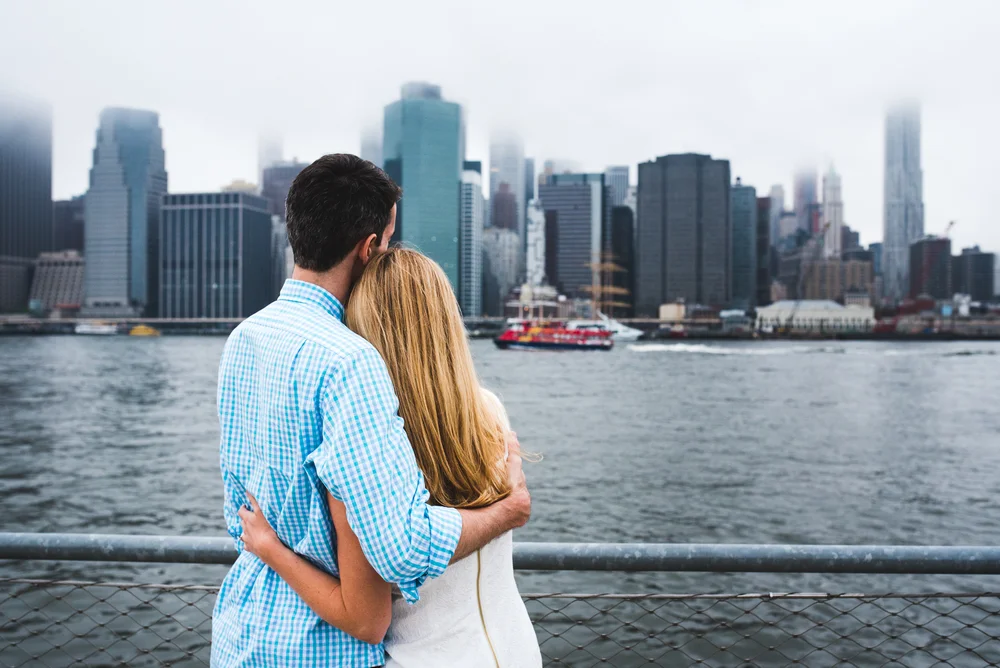 Creative Brooklyn engagement photo with a couple and the New York skyline