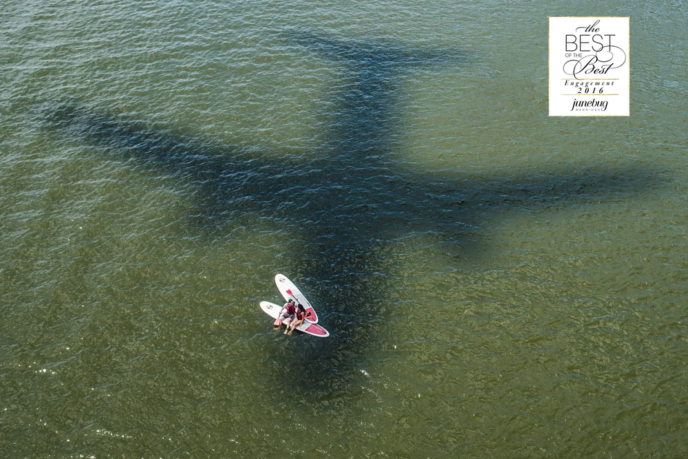 A couple on paddle boards beneath the shadow of a bridge