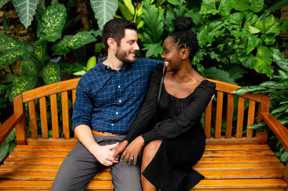  In this images, Matt and Furaha are captured in a romantic embrace amidst the beautiful setting of the botanical garden in Washington, D.C. The lush greenery and colorful flowers provide a stunning backdrop for their special moment. The couple's lov