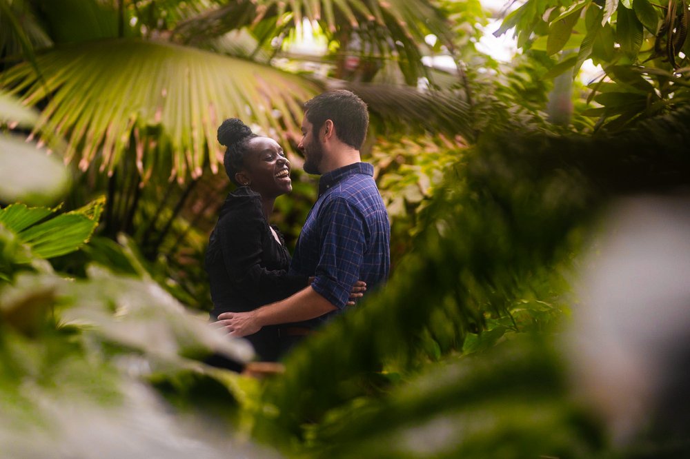  In this images, Matt and Furaha are captured in a romantic embrace amidst the beautiful setting of the botanical garden in Washington, D.C. The lush greenery and colorful flowers provide a stunning backdrop for their special moment. The couple's lov