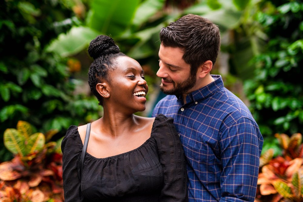  In this images, Matt and Furaha are captured in a romantic embrace amidst the beautiful setting of the botanical garden in Washington, D.C. The lush greenery and colorful flowers provide a stunning backdrop for their special moment. The couple's lov