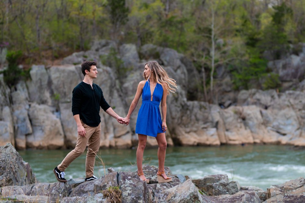  Kyle and Michela, who are celebrating their engagement with a photo session at the Billy Goat Trail. The theme of the session is the summer beach and the couple's journey towards a lifetime of love. It's a joyful and romantic occasion, and the Billy