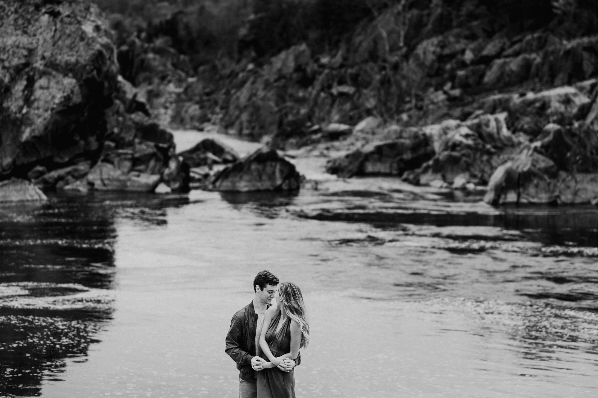  Kyle and Michela, who are celebrating their engagement with a photo session at the Billy Goat Trail. The theme of the session is the summer beach and the couple's journey towards a lifetime of love. It's a joyful and romantic occasion, and the Billy