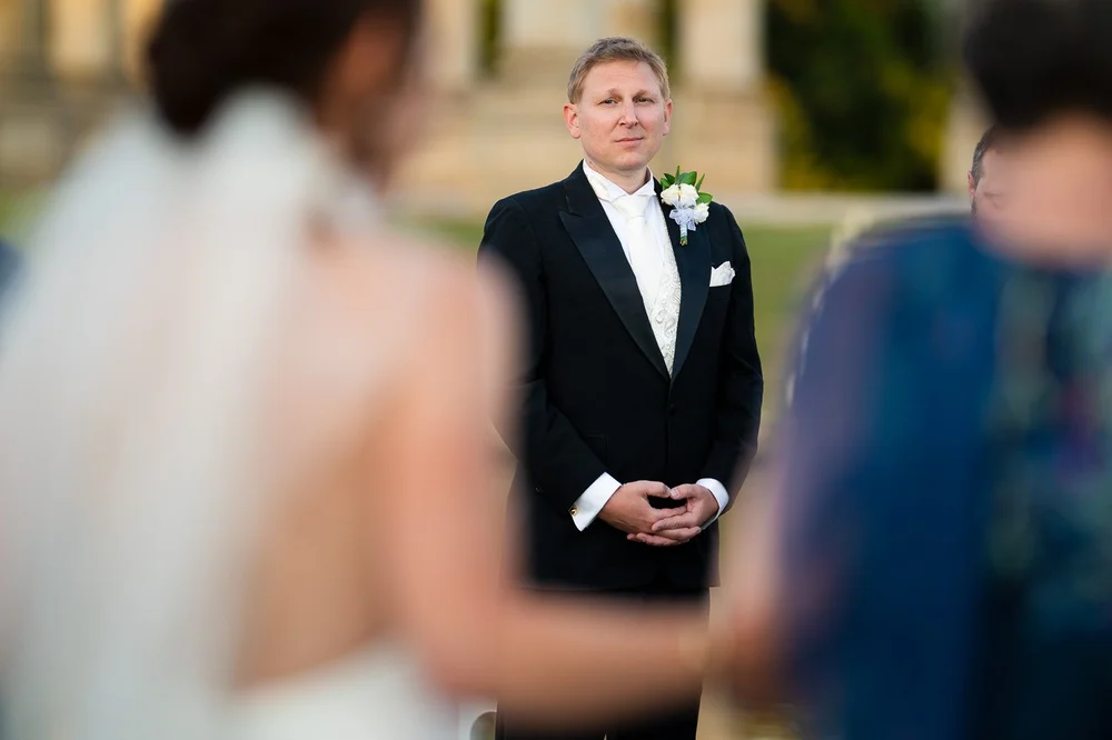 Groom watching the bride walk down the aisle during an outdoor National Arboretum wedding ceremony