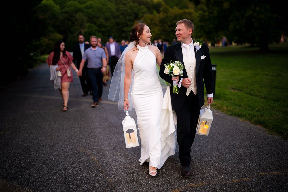 Newlyweds walking through glowing white lanterns during an evening National Arboretum wedding reception