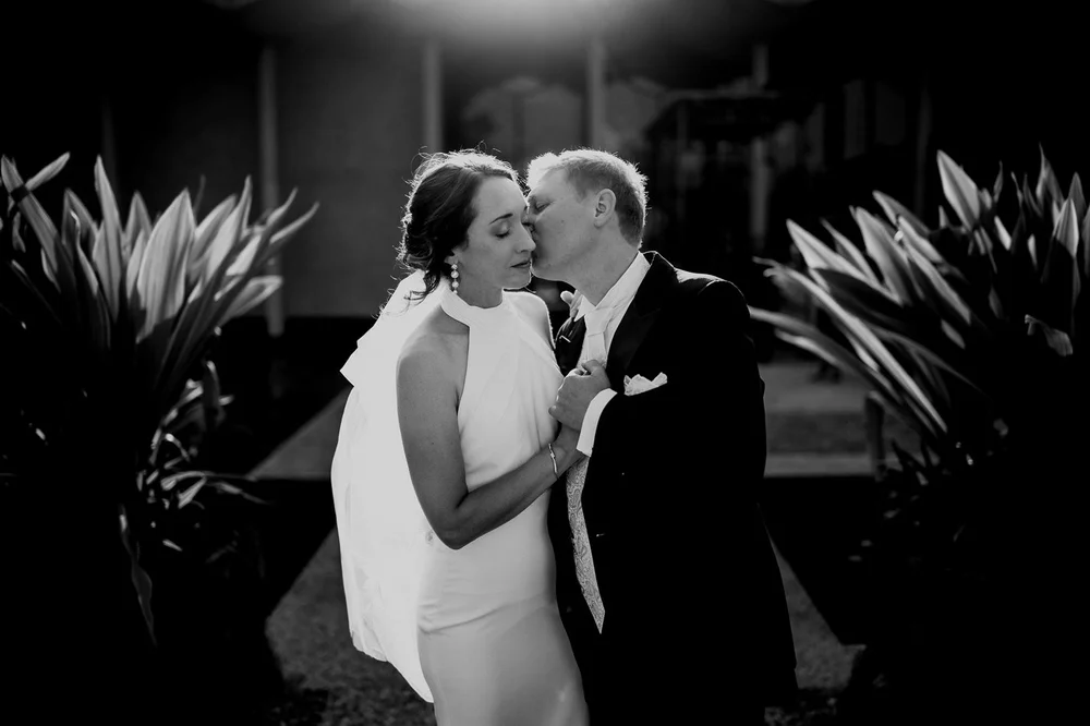 Black and white intimate garden kiss between bride and groom at the National Arboretum