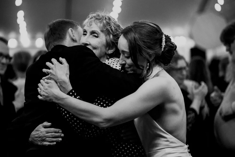 Emotional group hug between bride and family during a National Arboretum wedding reception