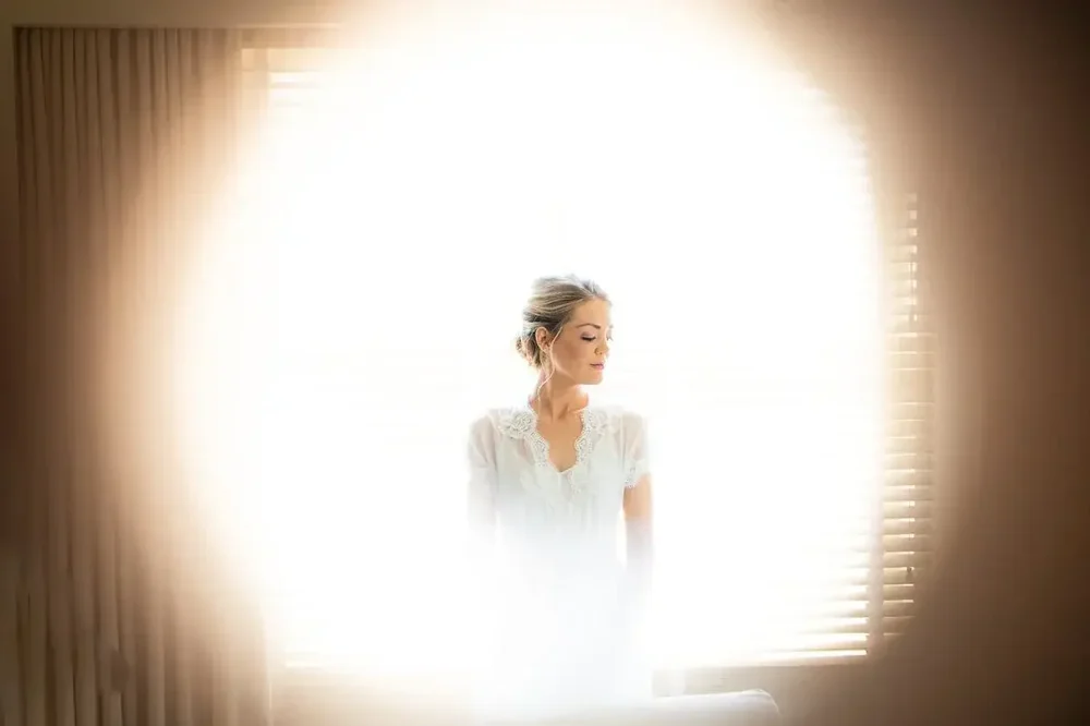 Bride glowing in soft window light wearing her getting ready robe before the Meridian House ceremony