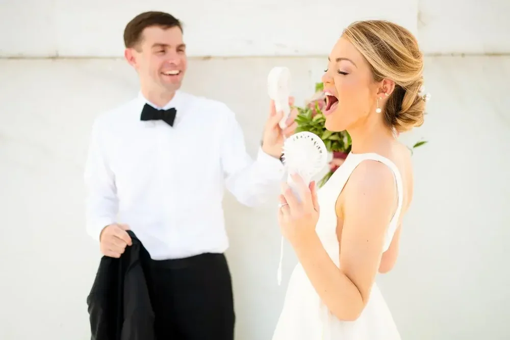 Bride and groom cooling off with handheld fans during their Meridian House wedding