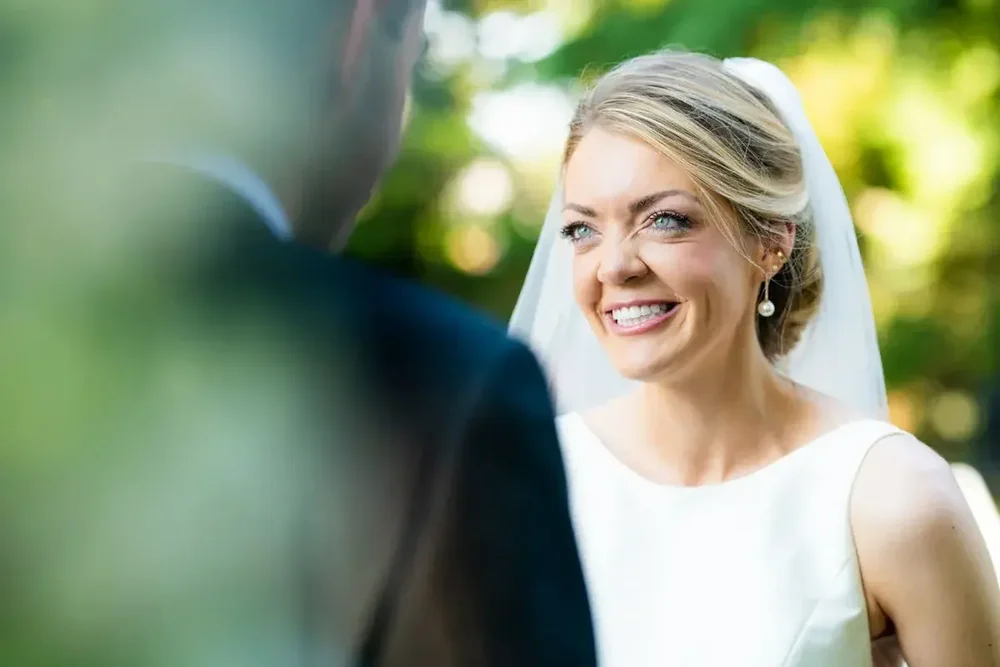 Bride smiles at her groom during the wedding ceremony at Meridian House