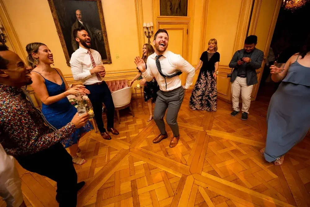 Groom dancing energetically with guests cheering him on at Meridian House