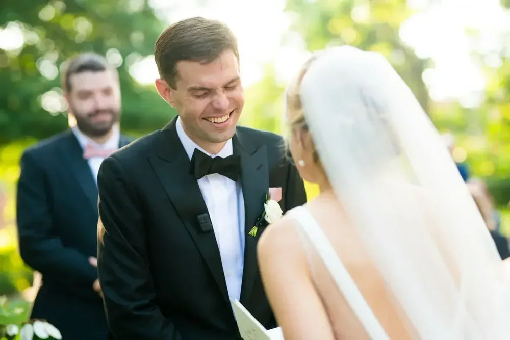 Groom laughs with joy during the outdoor wedding ceremony at Meridian House