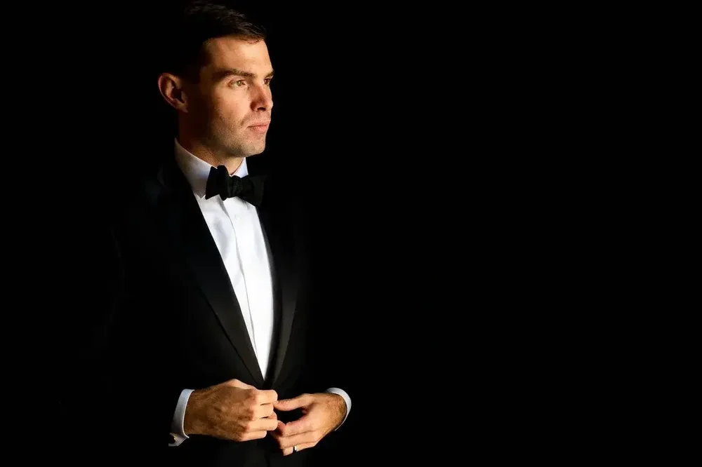 Groom in classic black tuxedo portrait with dramatic window light before the Meridian House wedding