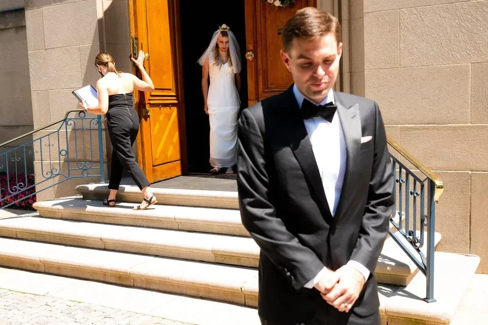 Groom waits with eyes closed as bride emerges for their first look outside Meridian House