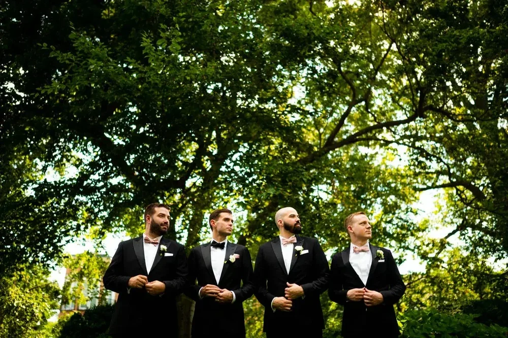 Groomsmen in tuxedos with pink bow ties at a Meridian House wedding