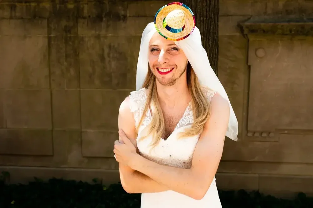 Groom playfully dresses in a wedding gown and tiny colorful hat at Meridian House in DC