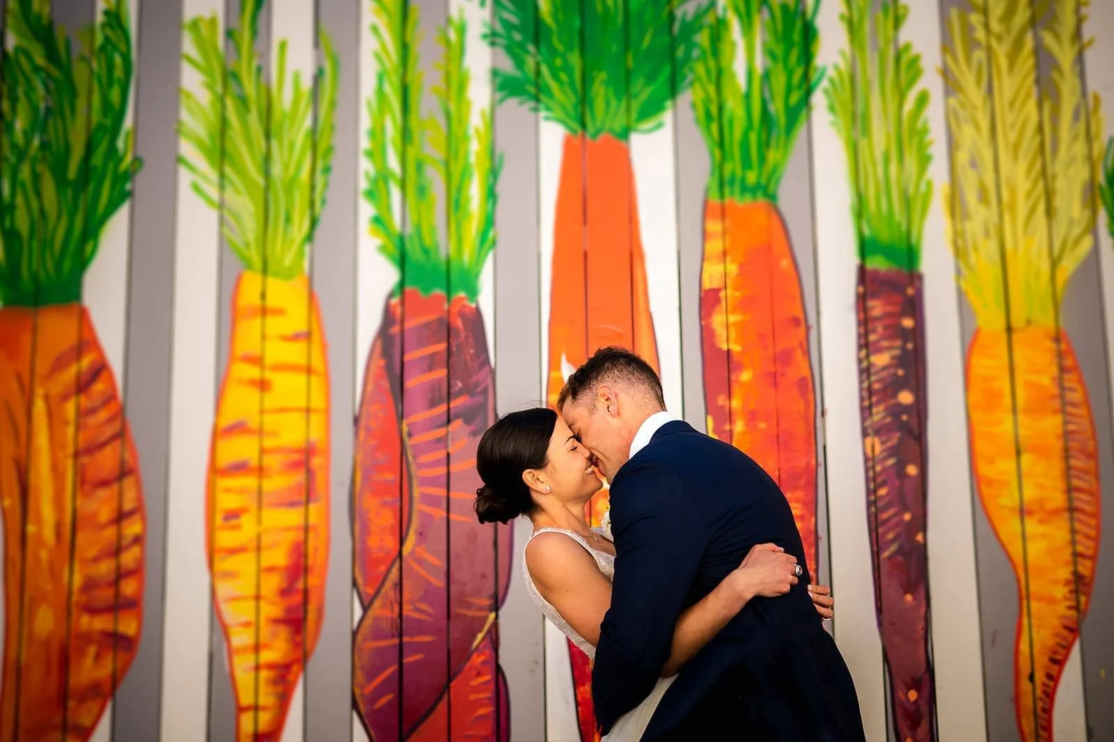 Urban art gallery wedding portrait in the heart of D.C. with a bride and groom laughing together in front of a colorful mural.