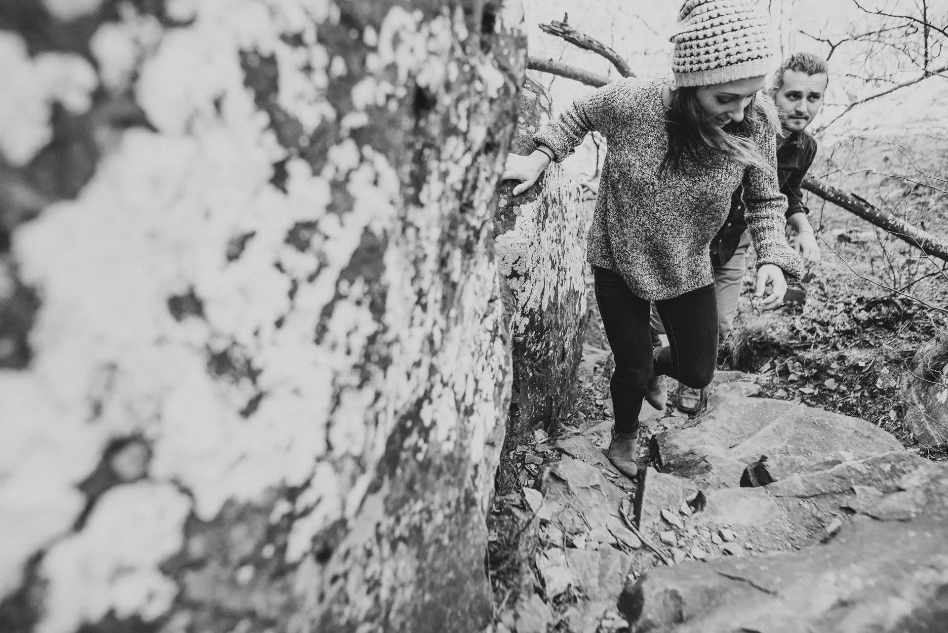 Black and white engagement photo of a couple hiking a rocky trail together in Shenandoah National Park during an adventurous session.