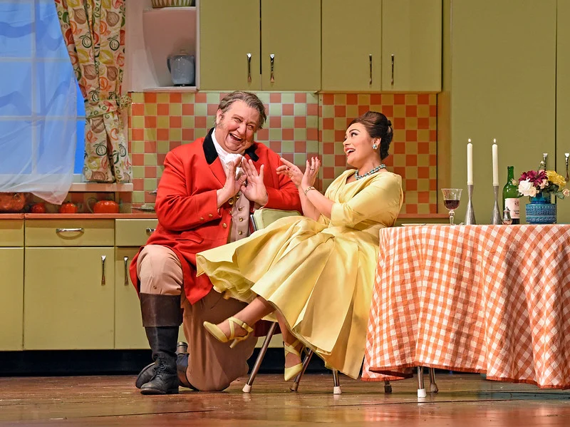Falstaff courts Alice Ford in her modern kitchen in Scene IV of Act I