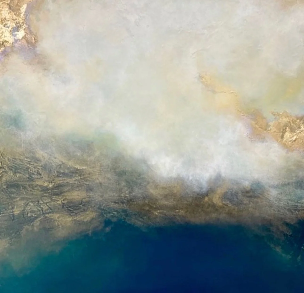 Aerial view of a volcanic eruption with ash and smoke billowing from the volcano into the sky over a body of water.