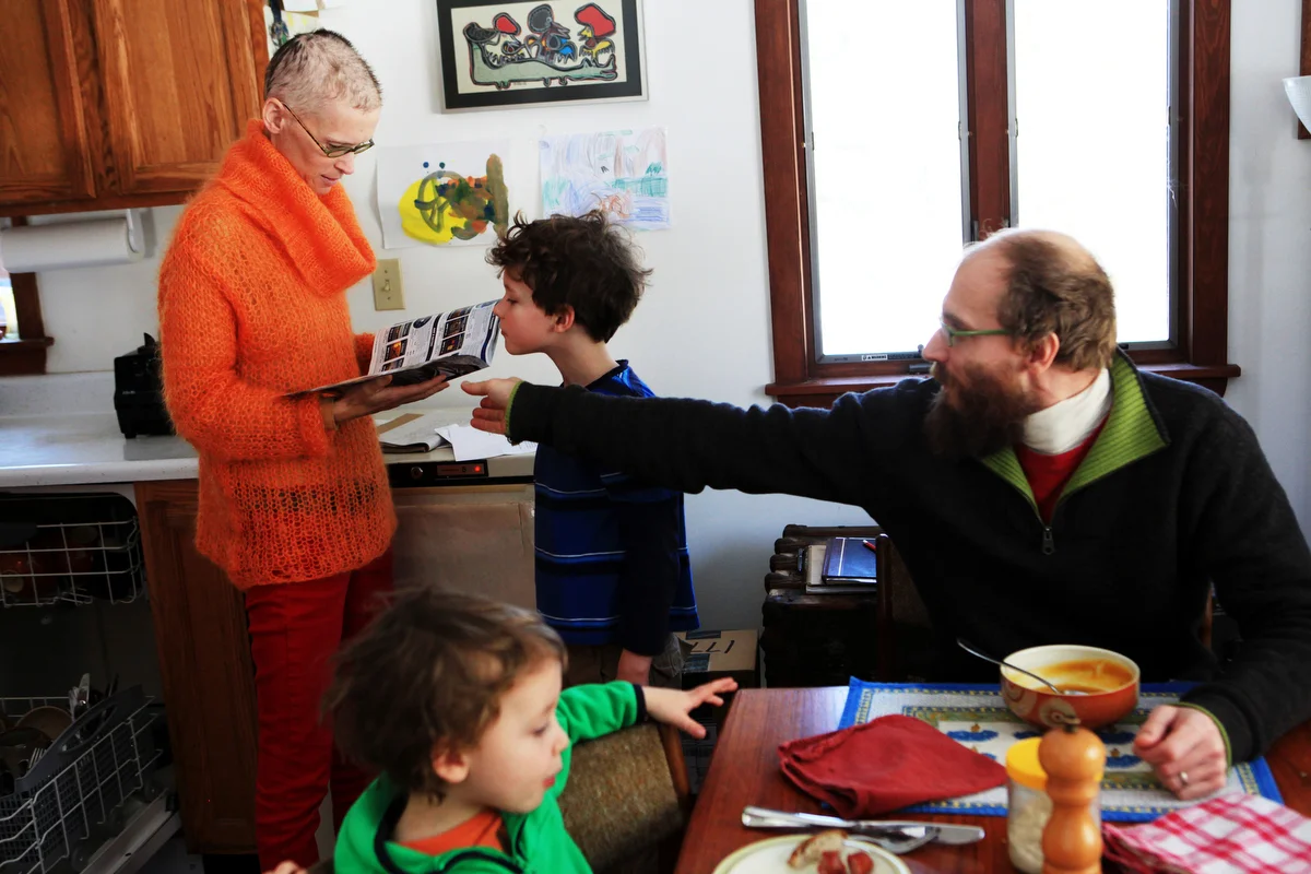  Sarah Thompson looks through a magazine as her son Wallace, 7, peeks over the top while her husband John and their other son Lysander, 4, ate lunch at their home in Georgetown, Maine on Friday, February 28, 2014. &nbsp;Sarah was diagnosed with leuke