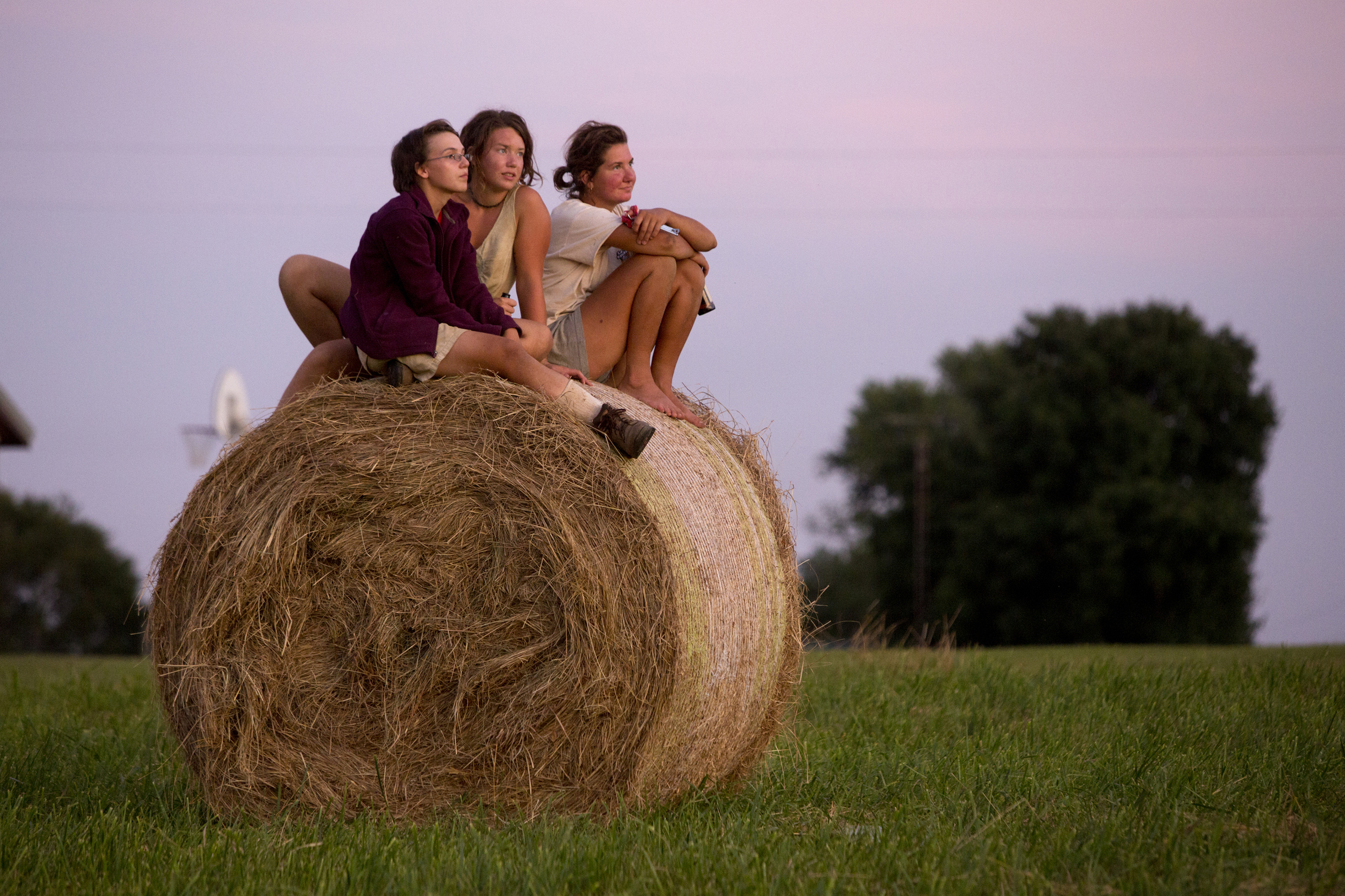  Living Roots Ecovillage farm apprentices Emily Spatt of Fort Wayne, left, Mecie Delffs of Grant Rapids, Mich., and Emily MacGibeny of New London, Conn. soak in the last rays of light across the street from the ecovillage in French Lick, Ind. on July