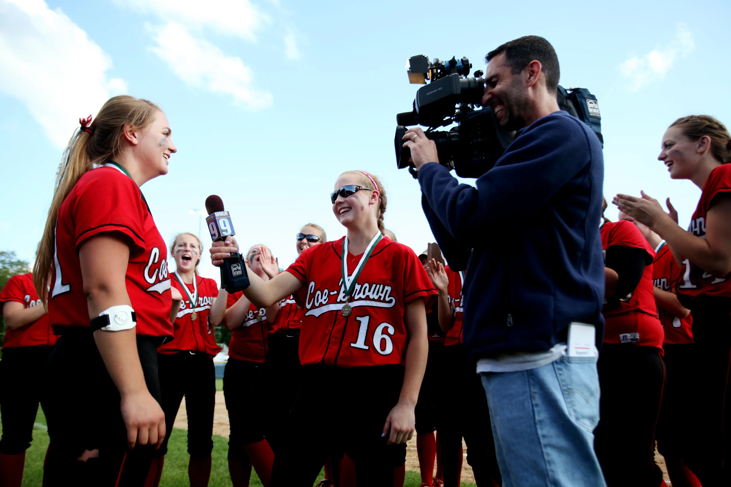  Coe-Brown's Catherine Langdon (middle) holds the microphone to teammate Lauren Jones as she is interviewed by WMUR's Jon Arnold after they won the Division II softball championship against John Stark at Southern New Hampshire University in  Hooksett