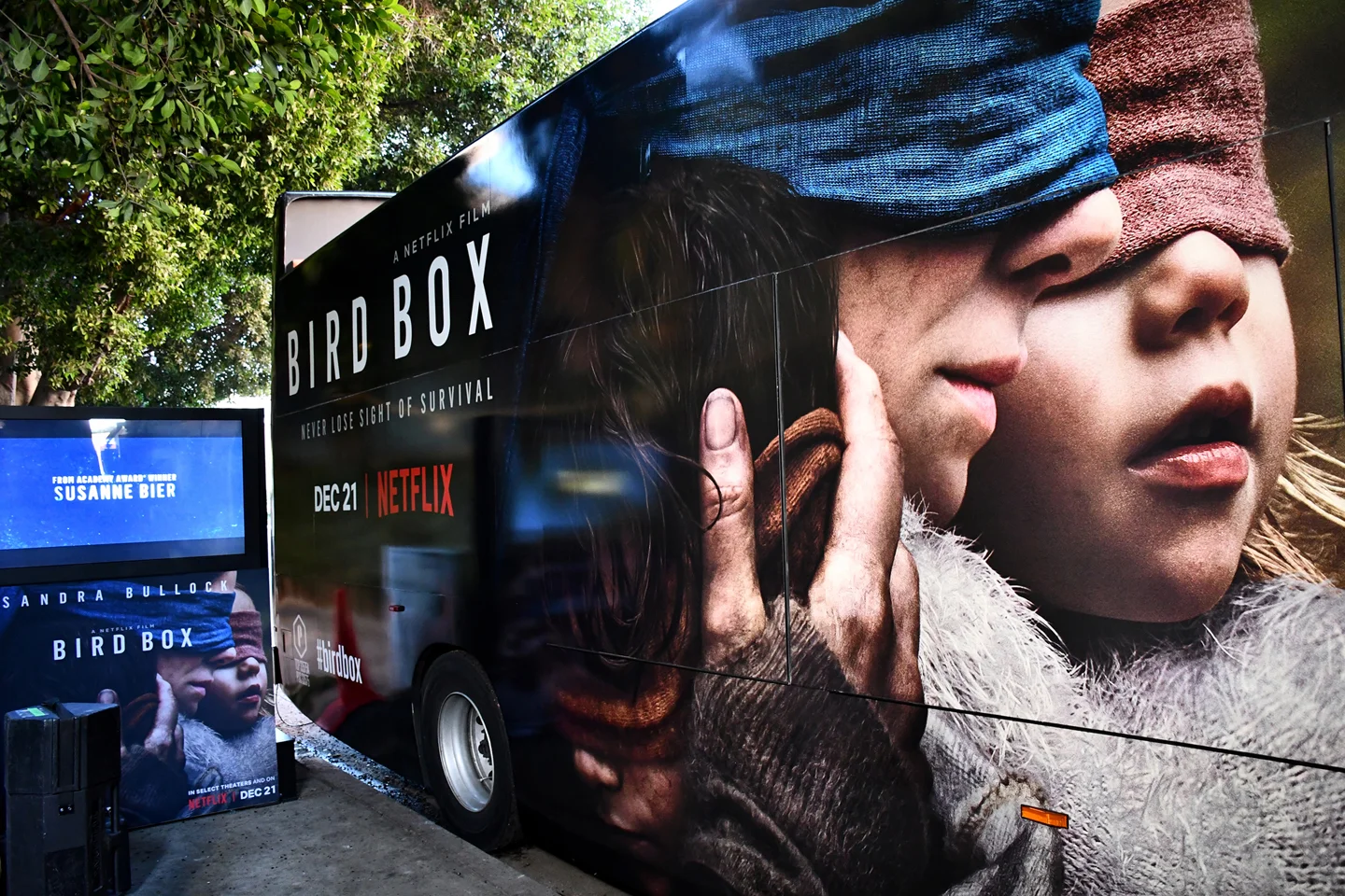 Promotional vehicle wrap for the Netflix film "Bird Box" featuring a close-up of a woman's face with her eyes covered by a cloth, held by a hand, with trees in the background.