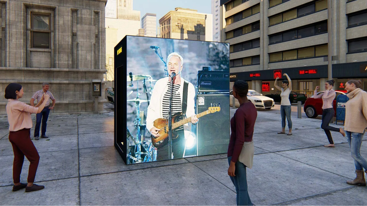 People in a city square watching a large outdoor screen showing a woman singing and playing guitar during a performance.