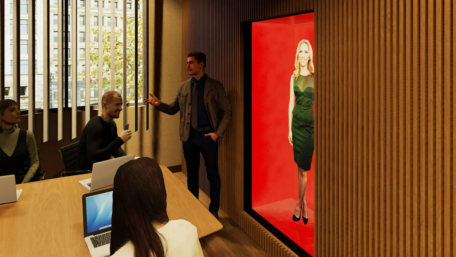 A conference room with four people, three women and one man, engaged in discussion. One woman is holding a phone, and her laptop is open on the table. The man is standing near a large red display with a woman in a green dress on it. The room has wood