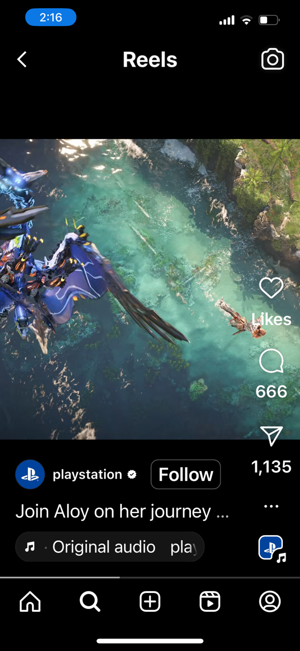 A scene from a video game showing a robotic character with blue and white armor flying over a turquoise body of water with rocks and greenery along the shoreline.