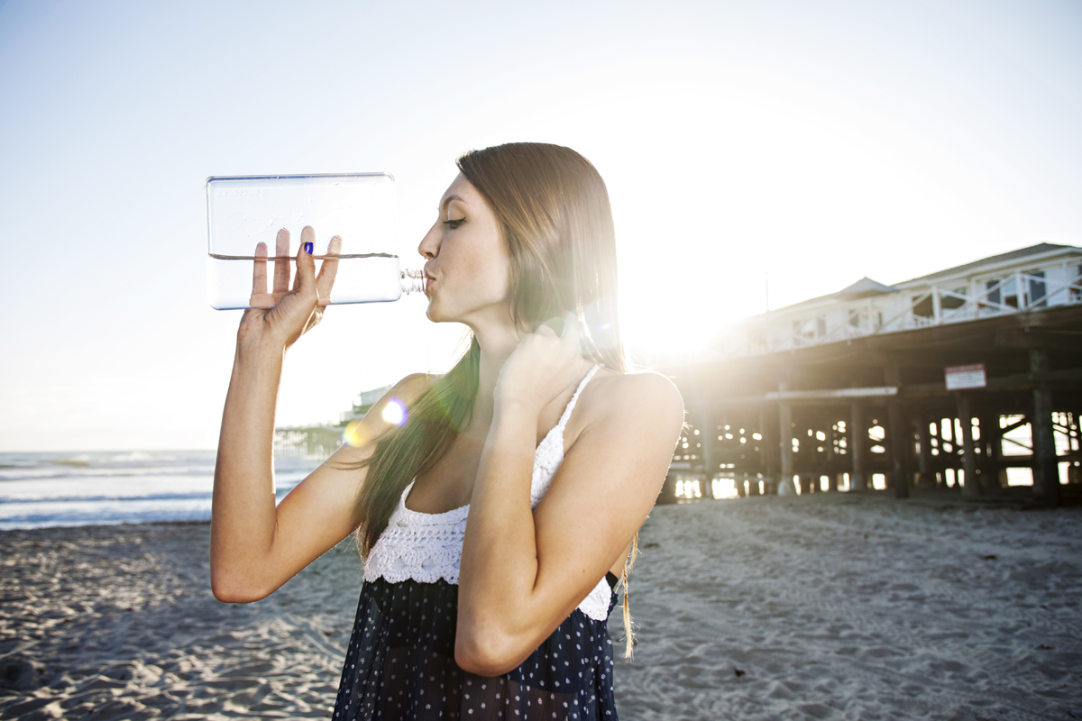 Cute girl drinking water at the beach. San Diego lifestyle, product and advertising photographer Jason Ward Studios.