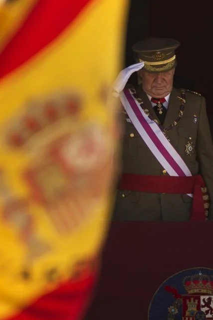 Andres Kudacki/The Associated Press King Juan Carlos salutes during a ceremony in Spain last week. His prestige stopped a military coup in the 1980s. Now he’s stepping down and Prince Felipe will assume the throne.