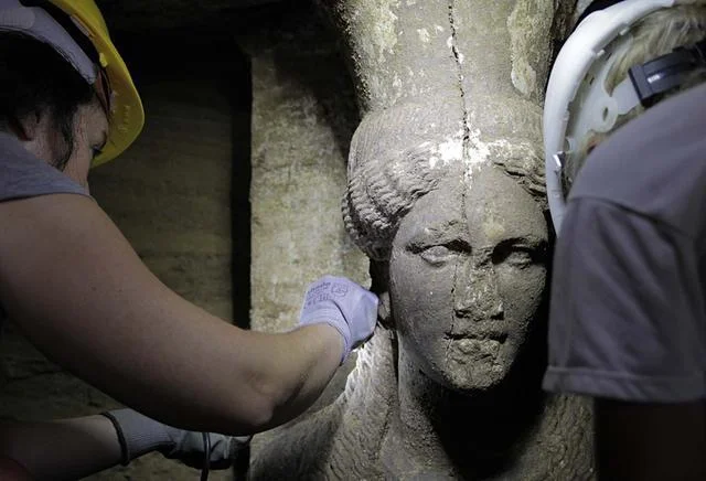 Greek Culture Ministry Archaeologists this month inspect a female figurine on a wall leading to the main room of an ancient tomb in Amphipolis, northern Greece.