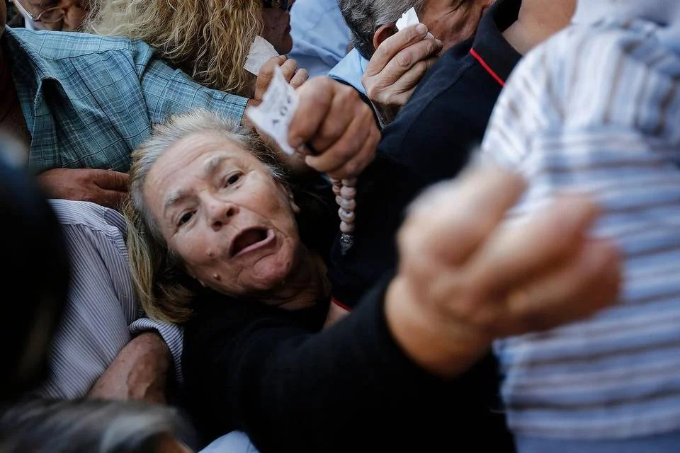 Pensioners wave ticket numbers as they try to get inside a National Bank of Greece branch in Athens last week. Elderly pensioners were stuck without monthly stipends as Greece deals with its financial crisis. | Simon Dawson Bloomberg News
