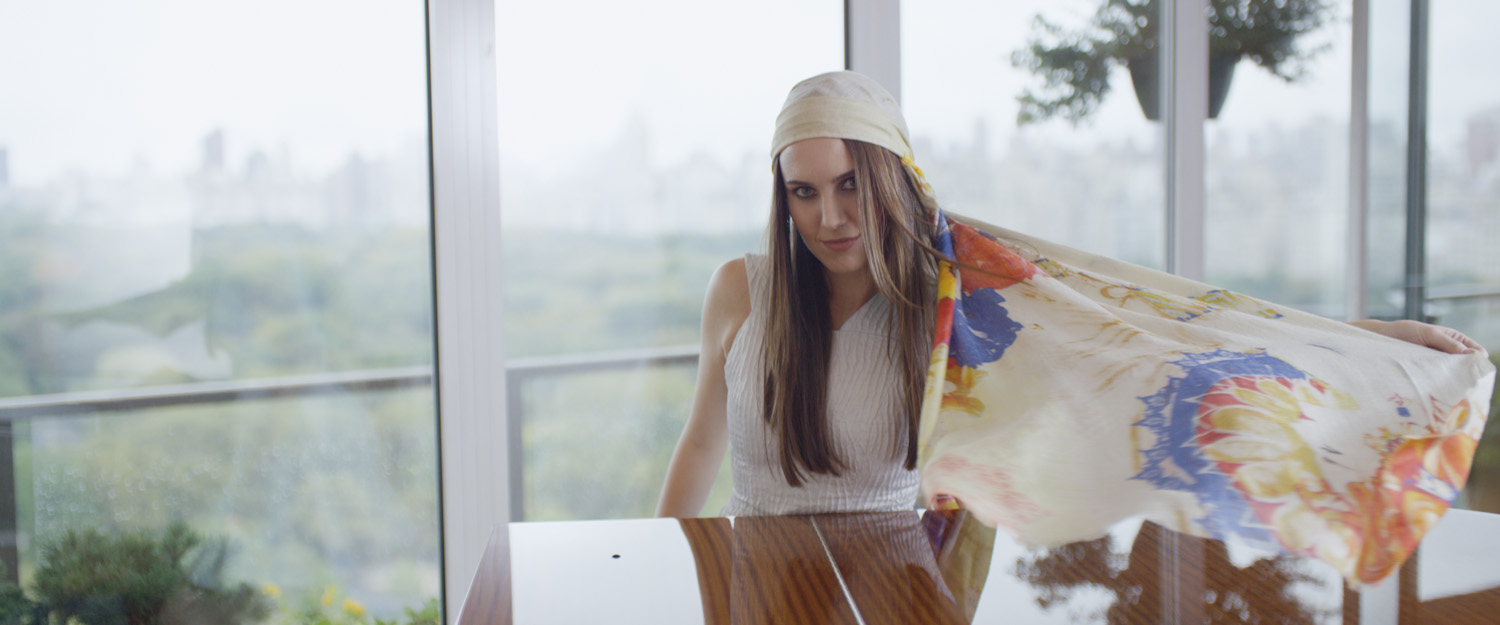 A woman wearing a headscarf sneaking a cloth over a dining table with a cityscape in the background.