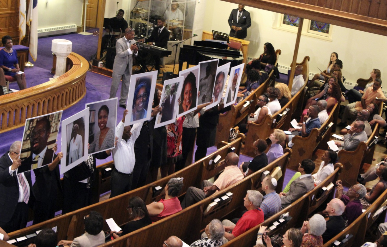 "Photos of the victims of the shooting at Emanuel AME Church in Charleston, S.C., are held during a vigil at the Metropolitan African Methodist Episcopal Church in Washington." (AP/ Washington Post )