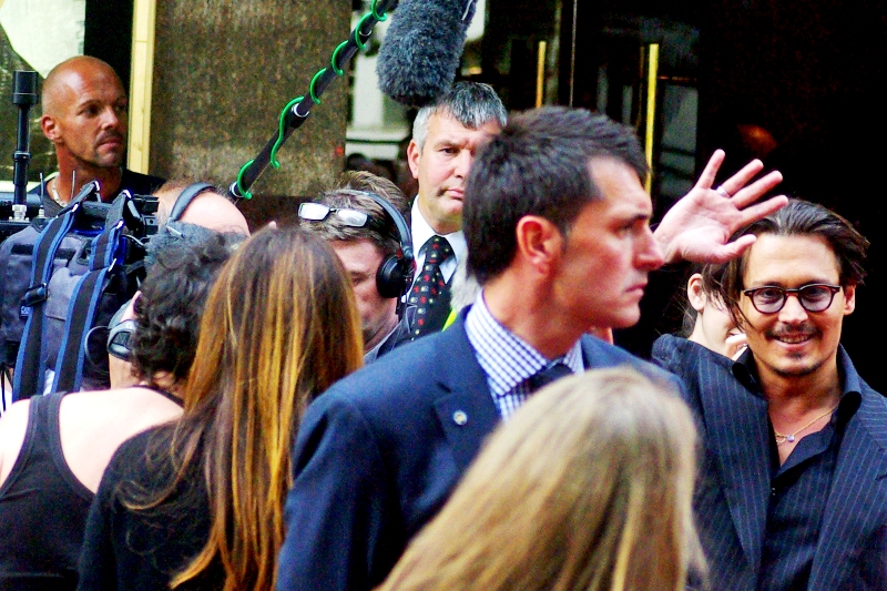 Johnny Depp manages a quick wave while his bodyguard lasers some poor fan into submission with an iron glare, perhaps