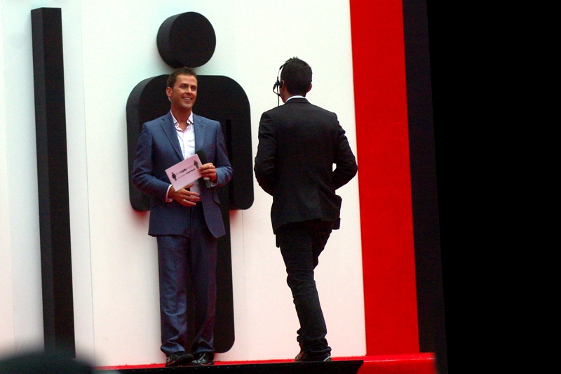 Our host today : Radio 1 DJ Scott Mills, perfectly framed by a "MAN" symbol, while another man approaches all... "my dark clothing matches it better". It's a low-key beginning to the premiere. Bear with me. It could get more exciting than this, although I promise nothing.