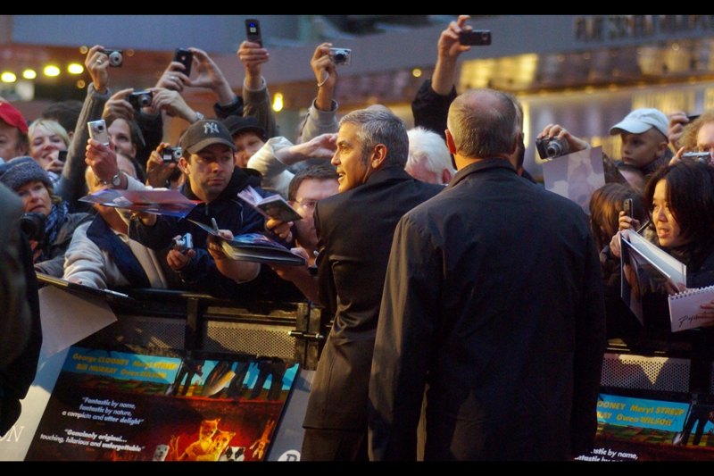 " Check this out, I'm signing without even looking!" There is a reason why George Clooney is capable of this feat...