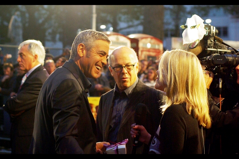 George Clooney may be sharing a laugh with a reporter, but I think the real story in this picture is the body language of the security dude in the background to the left...
