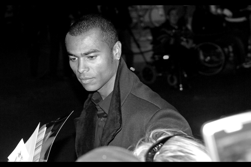 He's Ashley Cole, successful soccer player. (Oh, wait. I'm in England) *He's Ashley Cole, successful Football player.* Apparently Rio Ferdinand (the guy further up in the photos) is a financier/producer of the film.