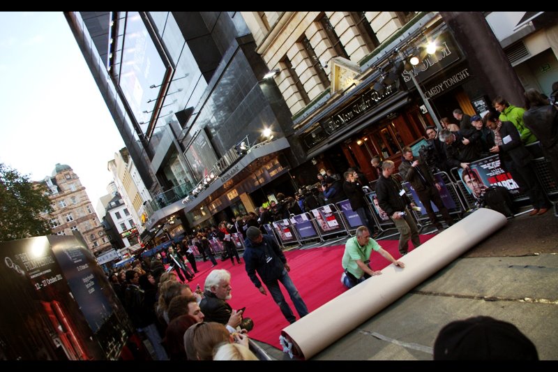 There are major refurbishment works in place for Leicester Square which meant that the construction works had to move their perimeter fencing back about a metre and a half AND fill open holes with tar and lay board just for the premiere before they could lay the red carpet. It's a 'behind-the-scenes' thing.