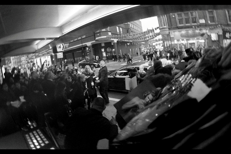 A car pulls up and dispenses Nicole Kidman. Disturbingly, at "last week's Baftas" they had riot-control style barriers - chest high and heavy. In contrast at most premieres they have fairly robust waist-high metal fences. However, at this one they only had bank branch style ropes! ... which is barely one step up from trying to keep rabid autograph dealers (or a barracuda swarm) at bay with polite language.