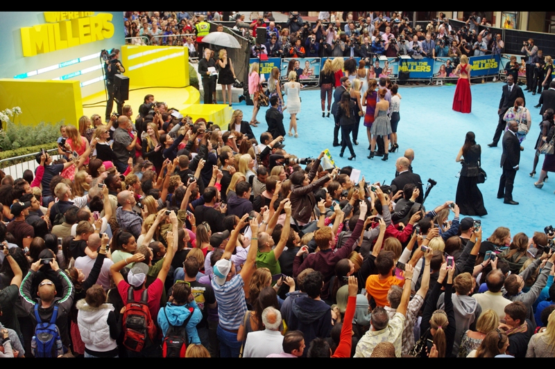 Jennifer Aniston approaches from the far right, and the crowd suddenly remembers that their mobile phones have cameras on them.